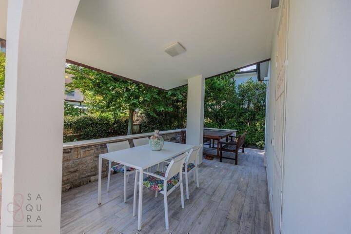 Überdachter Essbereich im Freien auf der Terrasse mit modernem weißen Tisch und Stühlen.
