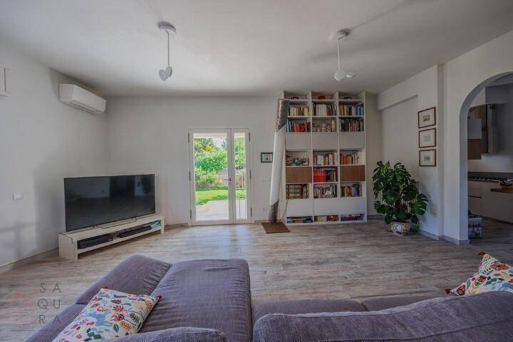Wohnzimmer mit Fernseher, Sofa und Bücherregal, mit direktem Zugang zum Garten.