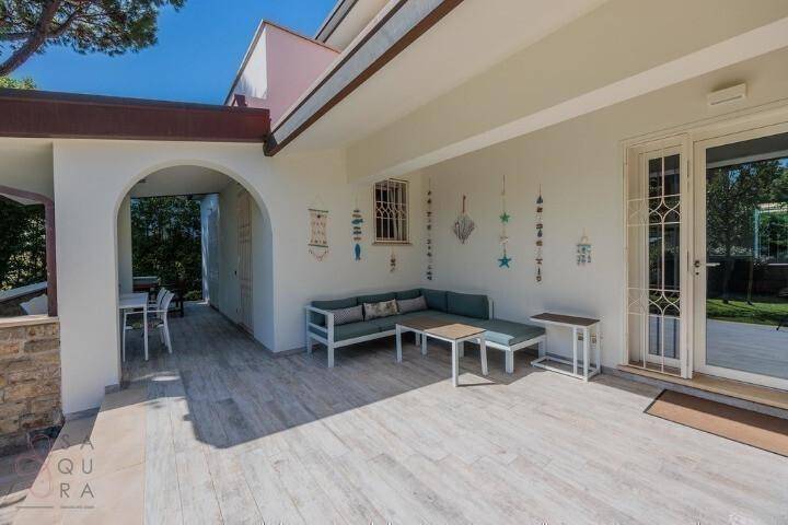 Gemütlicher überdachter Loungebereich auf der Terrasse mit Sofa und Beistelltischen für Entspannung.