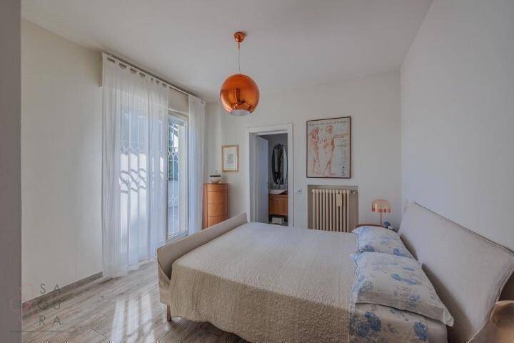 Schlafzimmer mit Doppelbett, Heizkörper und Zugang zu einem Balkon mit Tageslicht.