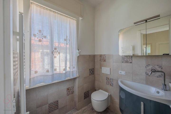 Badezimmer mit Wand-WC, modernem Waschbecken und Spiegelschrank über dem Waschtisch.