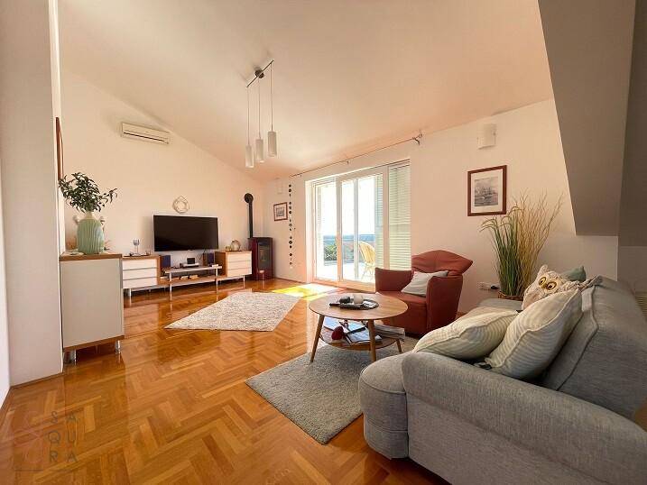 Helles Wohnzimmer mit Parkettboden, Dachschräge, modernem Holzofen und Klimaanlage.