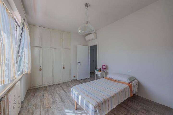Schlafzimmer mit Einzelbett, Einbauschränken und einem großen Fenster für viel Tageslicht.