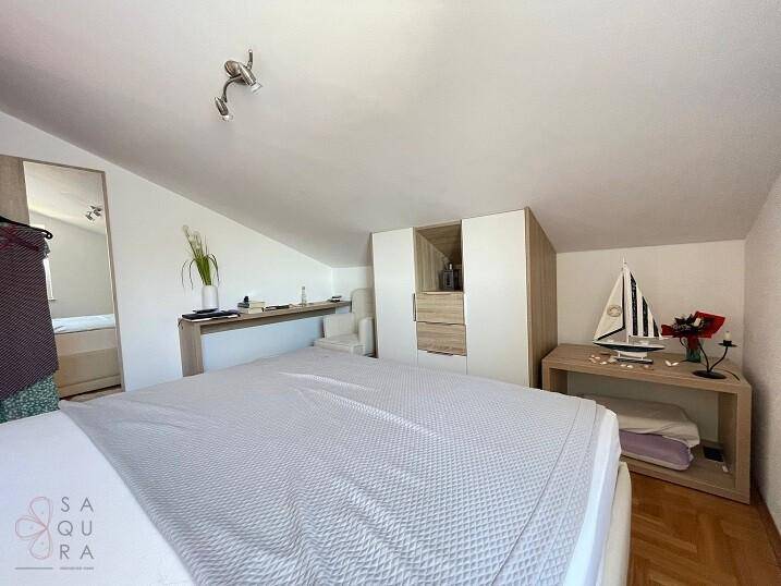 Schlafzimmer mit Dachschräge, Parkettboden und integrierten Schränken für Stauraum.