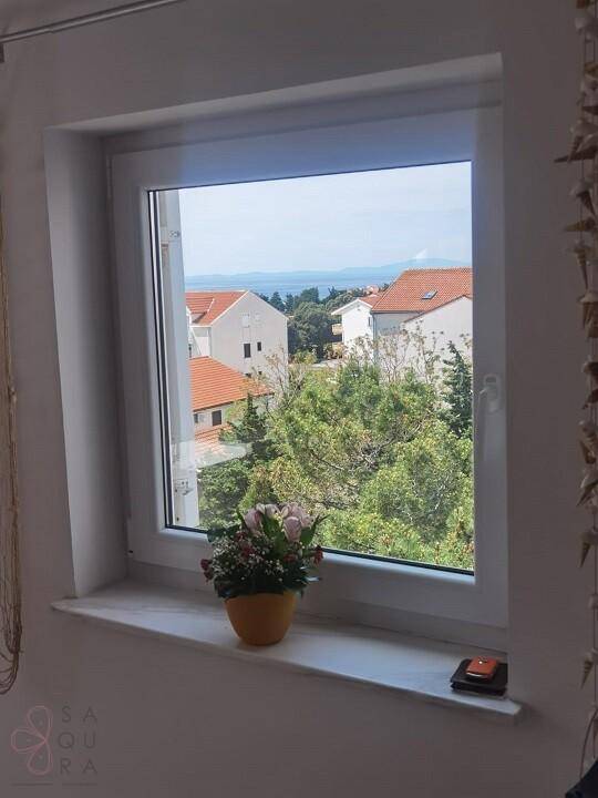 Fensterblick auf das Meer und die umliegende Wohnbebauung mit viel Grün.