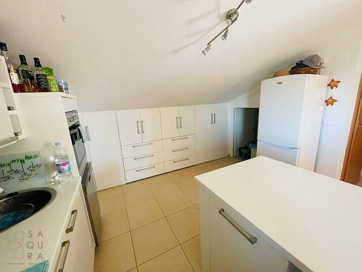 Helle Küche mit weißen Einbauschränken, Kühlschrank und praktischer Kücheninsel.