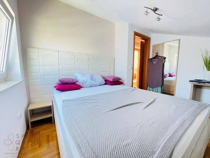 Gemütliches Schlafzimmer mit Parkettboden, Dachschräge und einem gepolsterten Kopfteil.