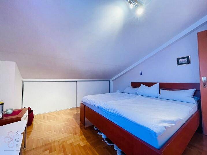 Schlafzimmer mit Parkettboden, Dachschräge und praktischen Schiebetürenschränken.