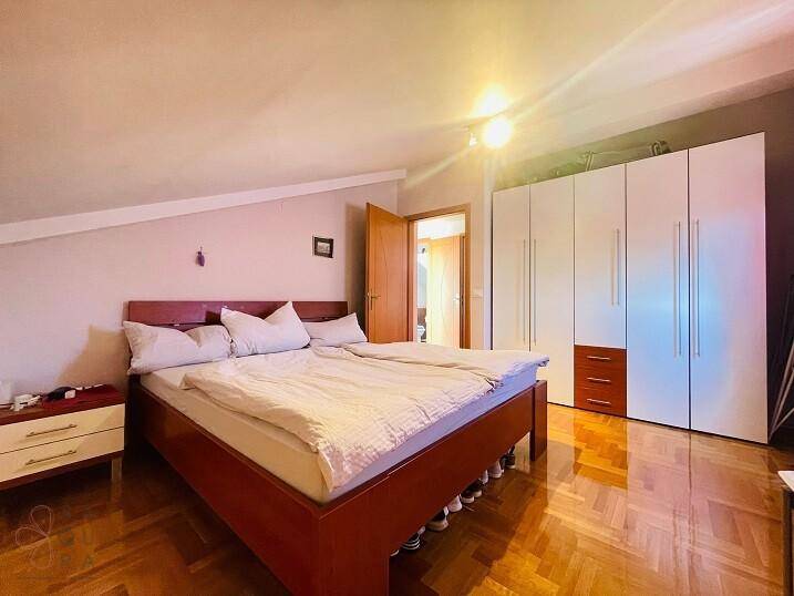 Geräumiges Schlafzimmer mit Parkettboden, Dachschräge und großem Kleiderschrank.