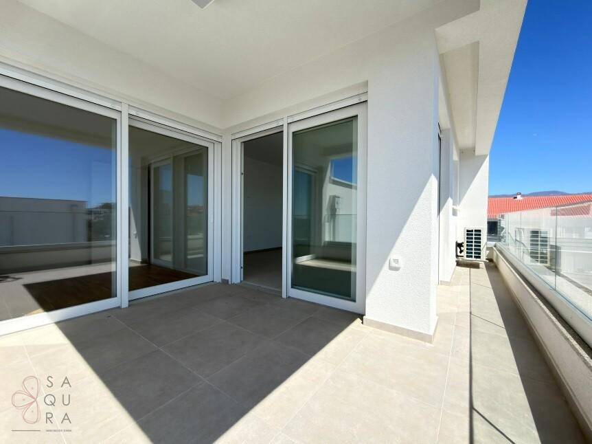 Großer Balkon mit Schiebetüren, Fliesenboden und viel Tageslicht.