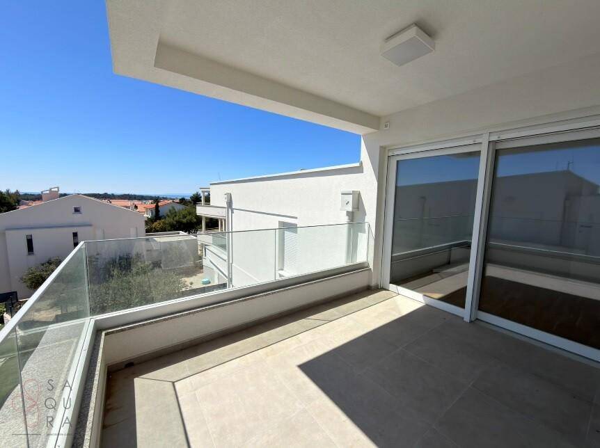 Heller Balkon mit Glasgeländer und weitem Blick über die Dächer der Nachbarschaft.