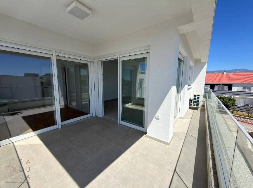 Großer Balkon mit Schiebetüren, Fliesenboden und Blick auf die Umgebung.