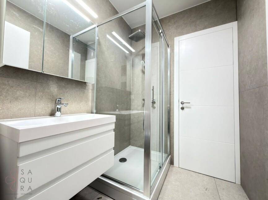 Modernes Badezimmer mit Duschkabine, Waschbecken und Spiegelschrank.