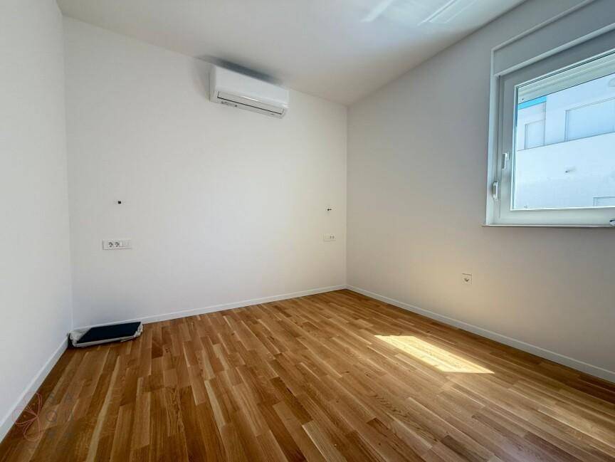 Heller Raum mit Holzboden, Klimaanlage und einem Fenster für Tageslicht.