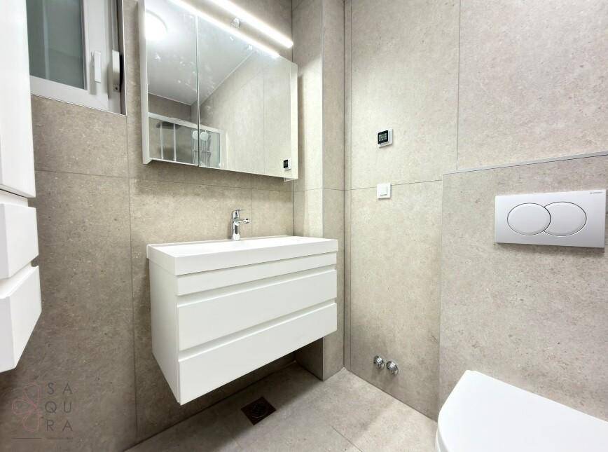Modernes Badezimmer mit Waschbecken, Spiegelschrank und wandhängendem WC.