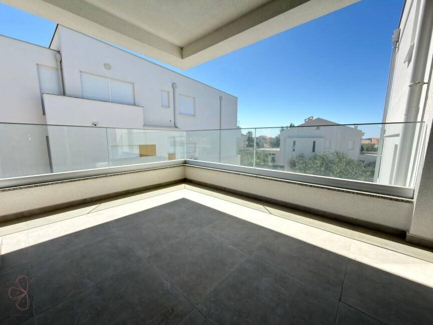 Geräumiger Balkon mit Glasgeländer und Blick auf die umliegenden Gebäude unter blauem Himmel.
