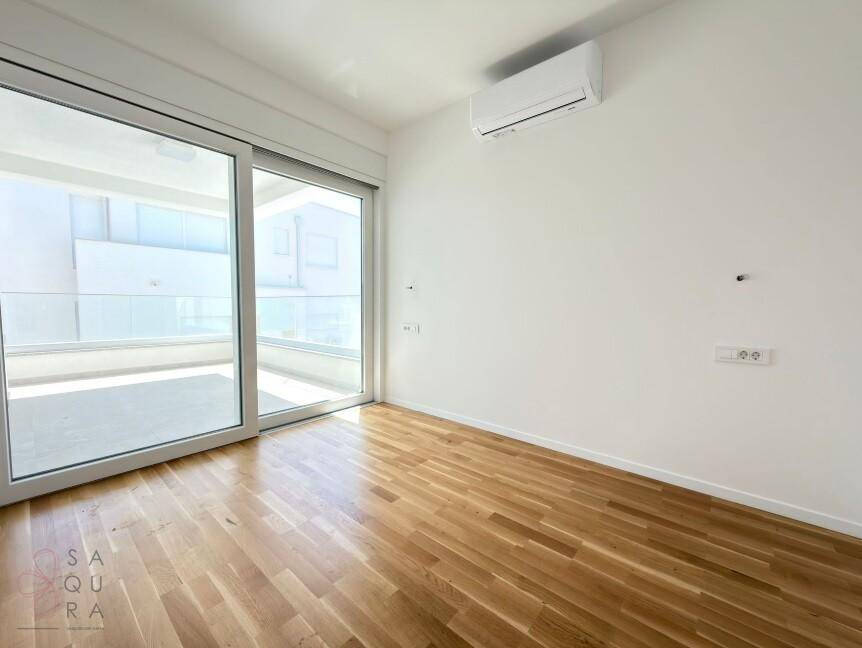 Modernes Schlafzimmer mit Holzboden, Klimaanlage und hellem Balkonzugang für angenehmes Wohnen.