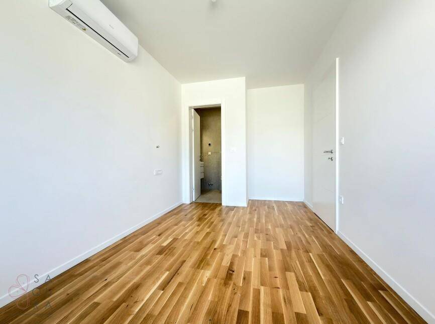 Helles Schlafzimmer mit Holzboden und direktem Zugang zum Badezimmer, ideal für Komfort.