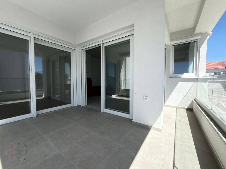 Heller Balkon mit großen Glasschiebetüren, die Zugang zu einem Innenraum bieten.