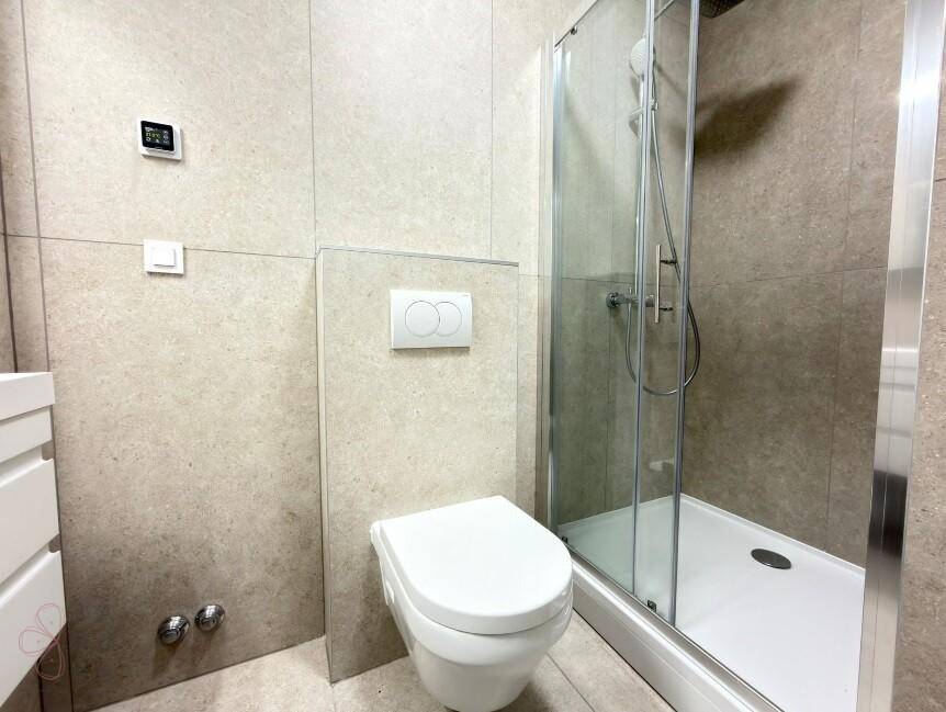 Modernes Badezimmer mit wandhängendem WC und Duschkabine, ausgestattet mit eleganten Fliesen.
