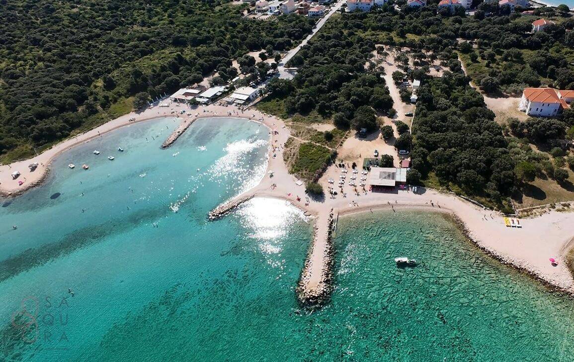Luftaufnahme einer malerischen Bucht mit türkisblauem Wasser und grüner Küstenlandschaft.