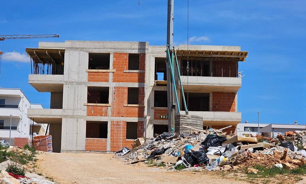 Baustelle eines Apartmentgebäudes mit sichtbaren Ziegelwänden und Betonstrukturen.