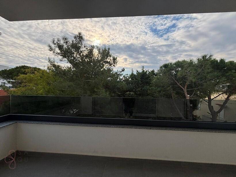 Weitläufiger Ausblick vom Balkon auf üppige Bäume und den bewölkten Himmel.