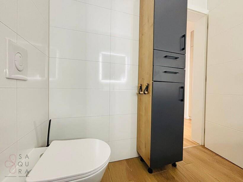 Badezimmer mit wandhängendem WC und einem hohen, modernen Badschrank.