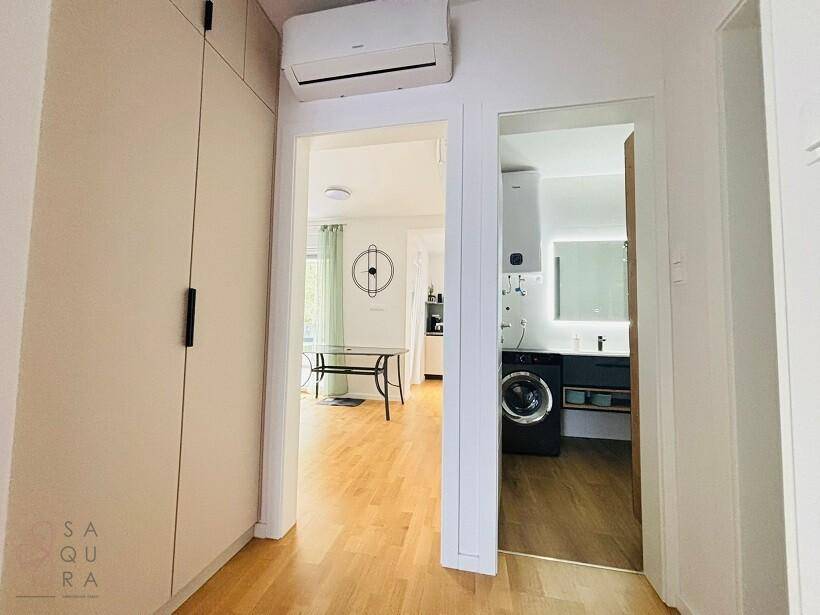 Heller Flur mit Einbauschränken und Blick in den Wohnbereich sowie das Badezimmer.