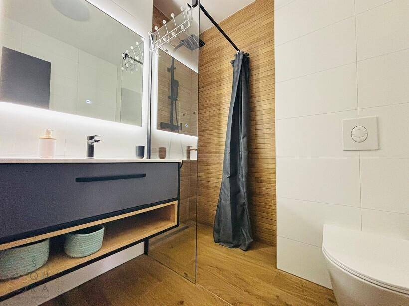 Modernes Badezimmer mit begehbarer Dusche, Waschtisch und wandhängendem WC.