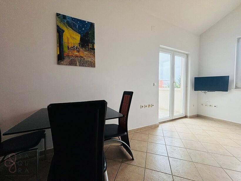 Heller Wohn-Essbereich mit Fliesenboden, Esstisch und Zugang zu einem Balkon.