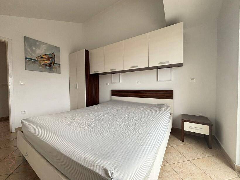 Schlafzimmer mit Doppelbett, Einbauschränken über dem Bett und Fliesenboden.