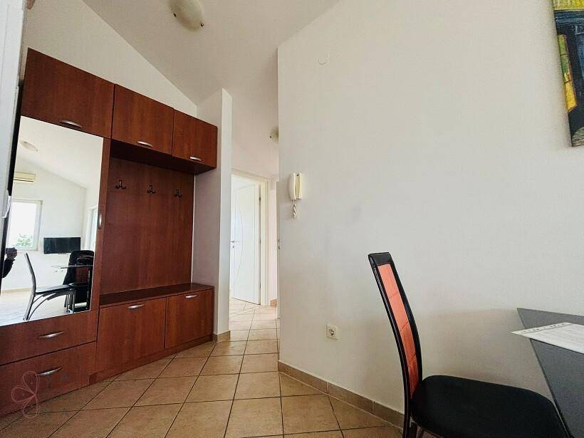 Eingangsbereich mit praktischer Holzgarderobe, Spiegel und Fliesenboden.