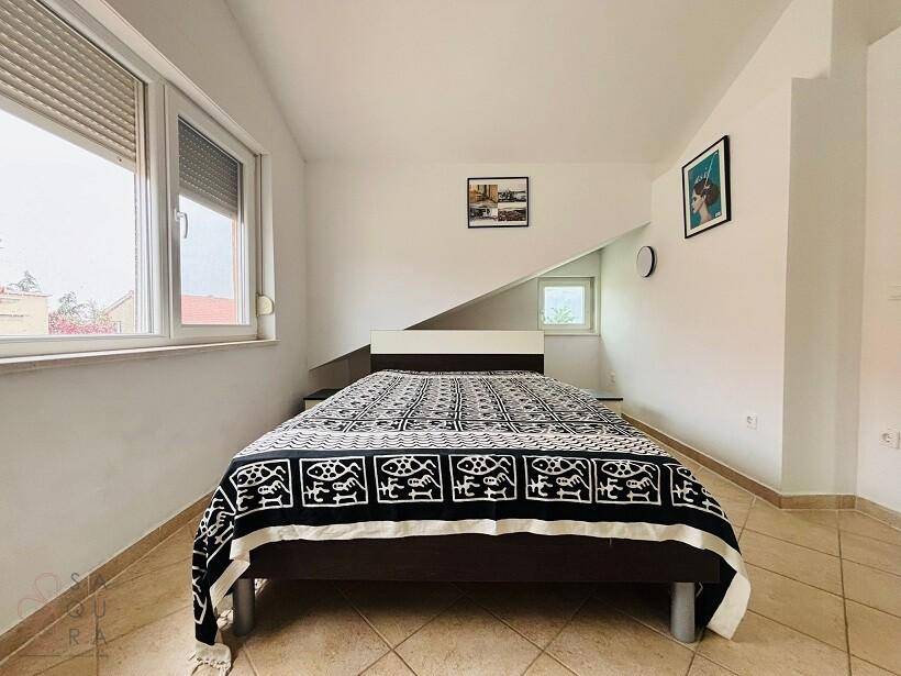 Schlafzimmer mit Doppelbett, Dachschräge und Fenstern mit Rollläden.