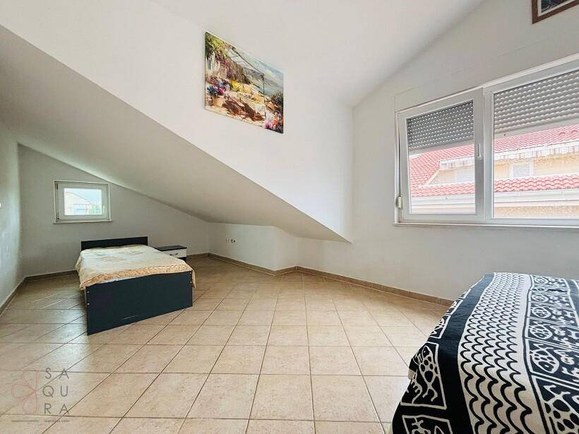 Helles Schlafzimmer mit zwei Betten, Dachschräge und Fenstern mit Rollläden.