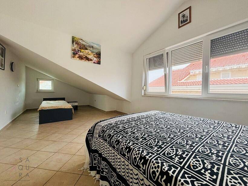 Geräumiges Schlafzimmer mit zwei Betten, Dachschräge und Fenstern mit Rollläden.