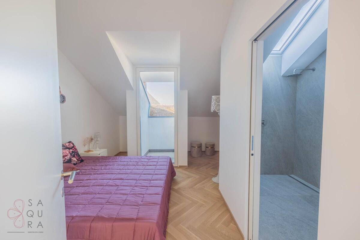 Geräumiges Schlafzimmer mit Doppelbett, Holzboden und Zugang zu einem kleinen Balkon.