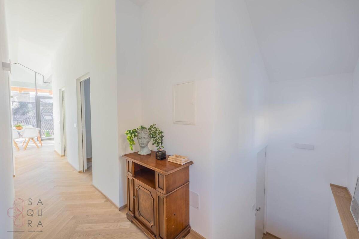 Heller Flur mit Fischgrätparkett und einem antiken Holzschrank, der zum Wohnbereich führt.