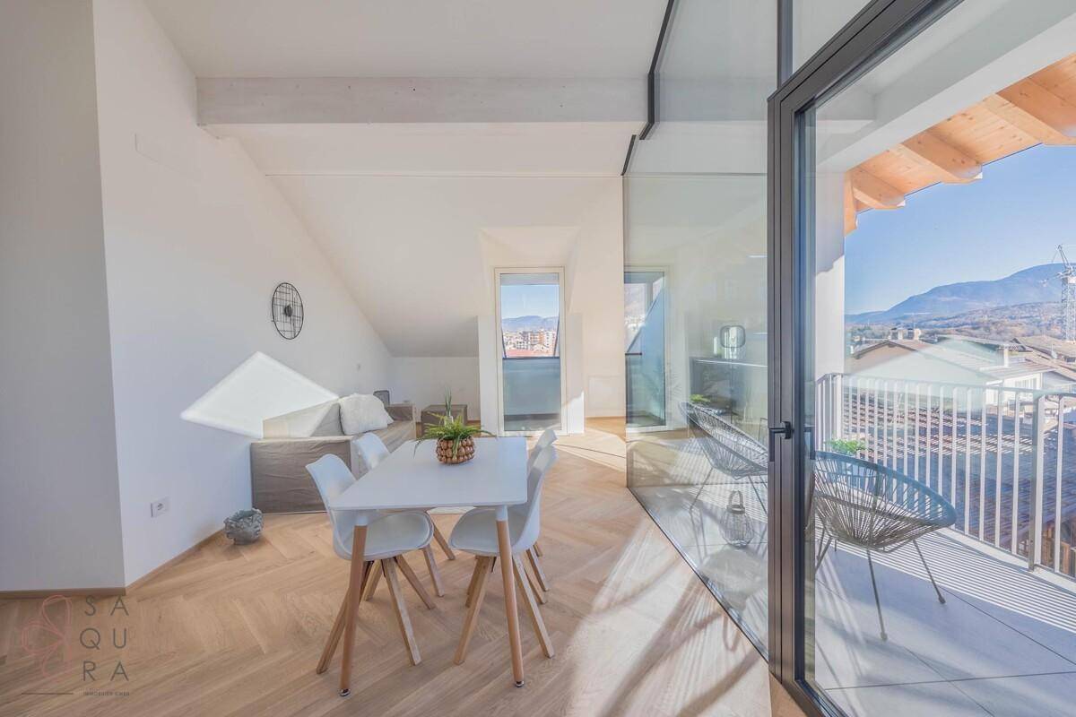 Offener Wohn- und Essbereich mit Holzboden, moderner Einrichtung und Zugang zum Balkon.