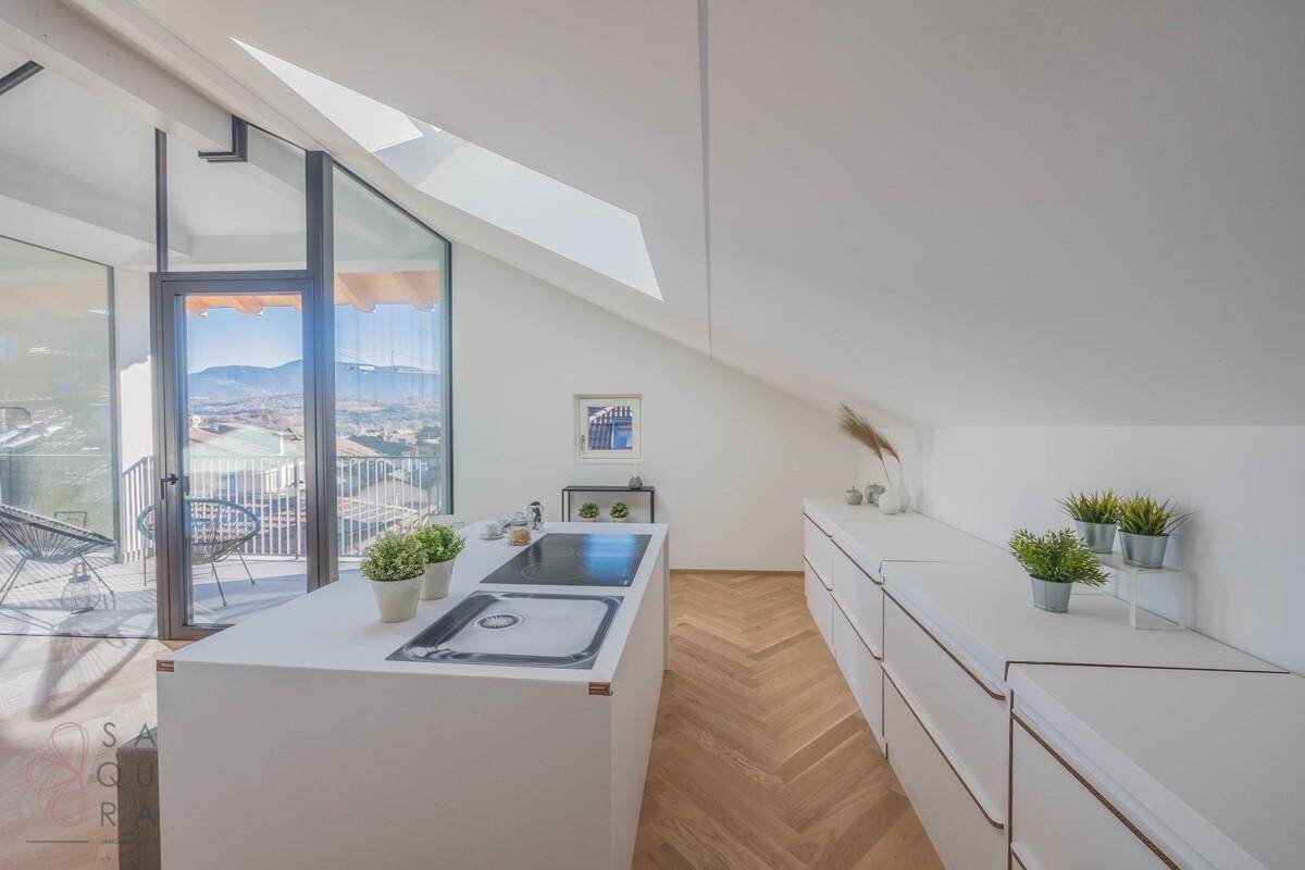 Helle, minimalistische Küche mit weißer Küchenzeile, viel Stauraum und Dachfenster.