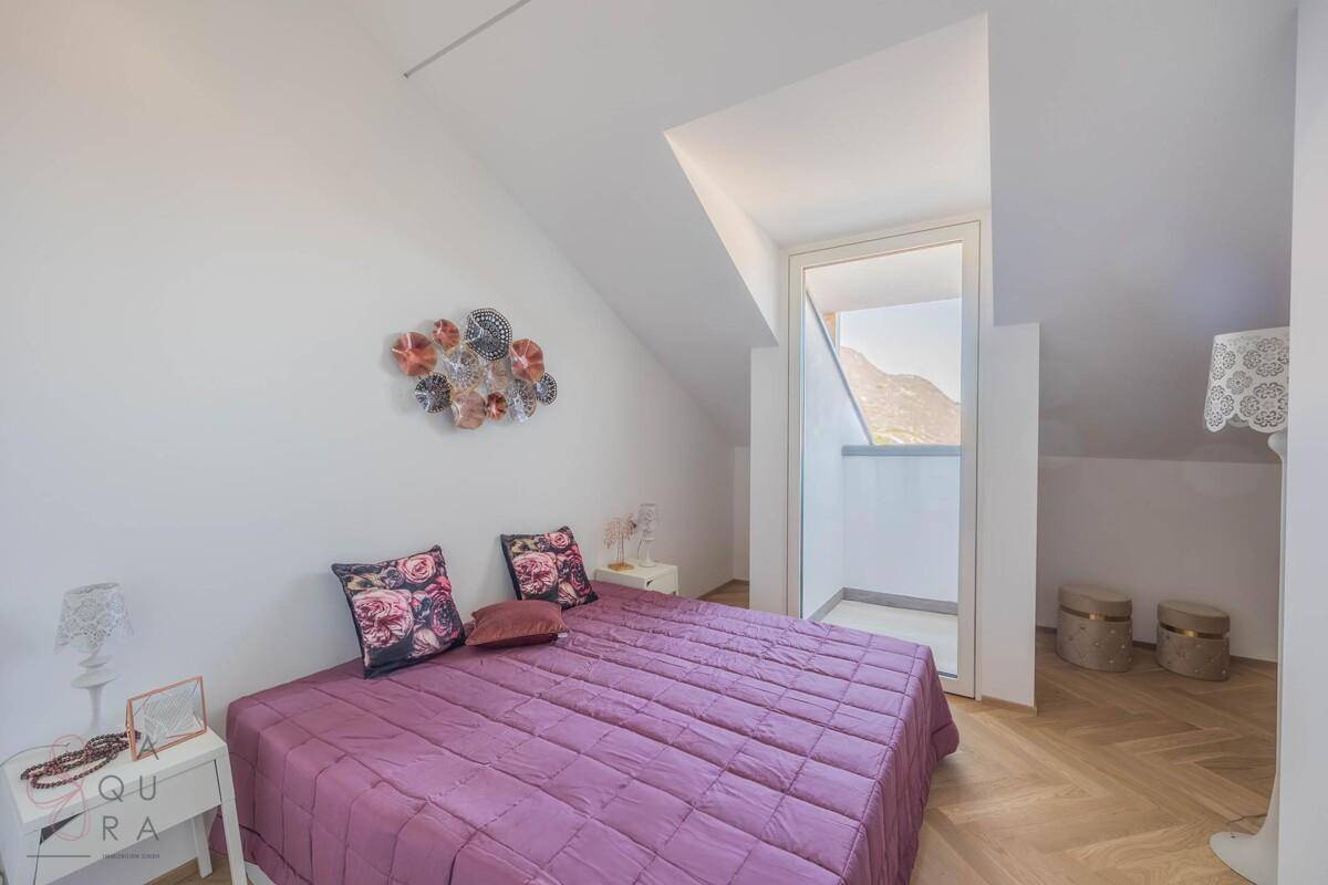 Gemütliches Schlafzimmer mit Doppelbett, Holzboden und Zugang zu einem kleinen Balkon.
