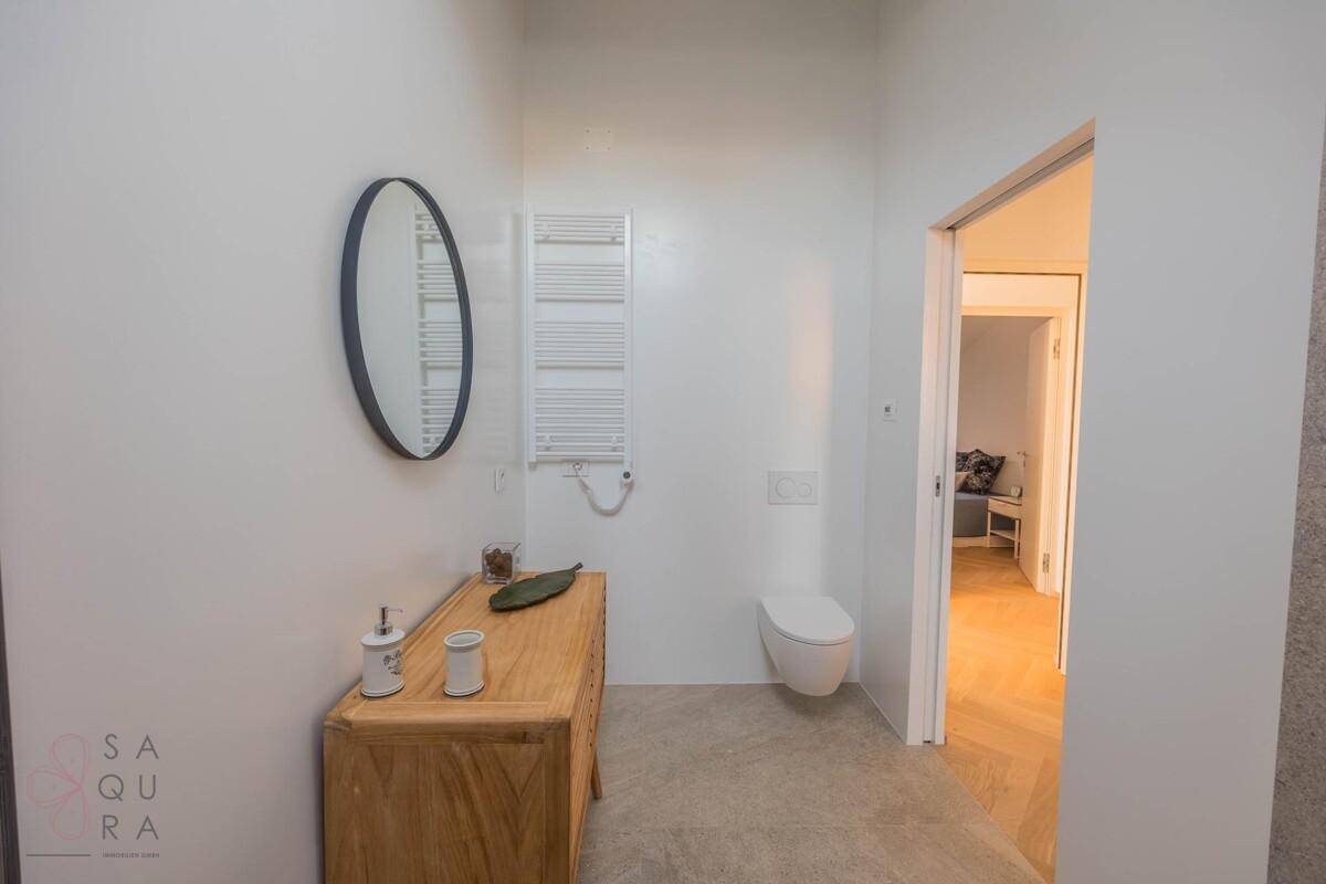 Helles Badezimmer mit modernem Waschtisch, Wand-WC und beheiztem Handtuchhalter.