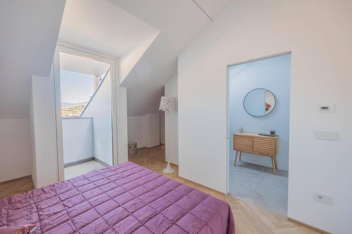 Schlafzimmer mit Doppelbett, Holzboden und Blick auf das angrenzende Badezimmer.