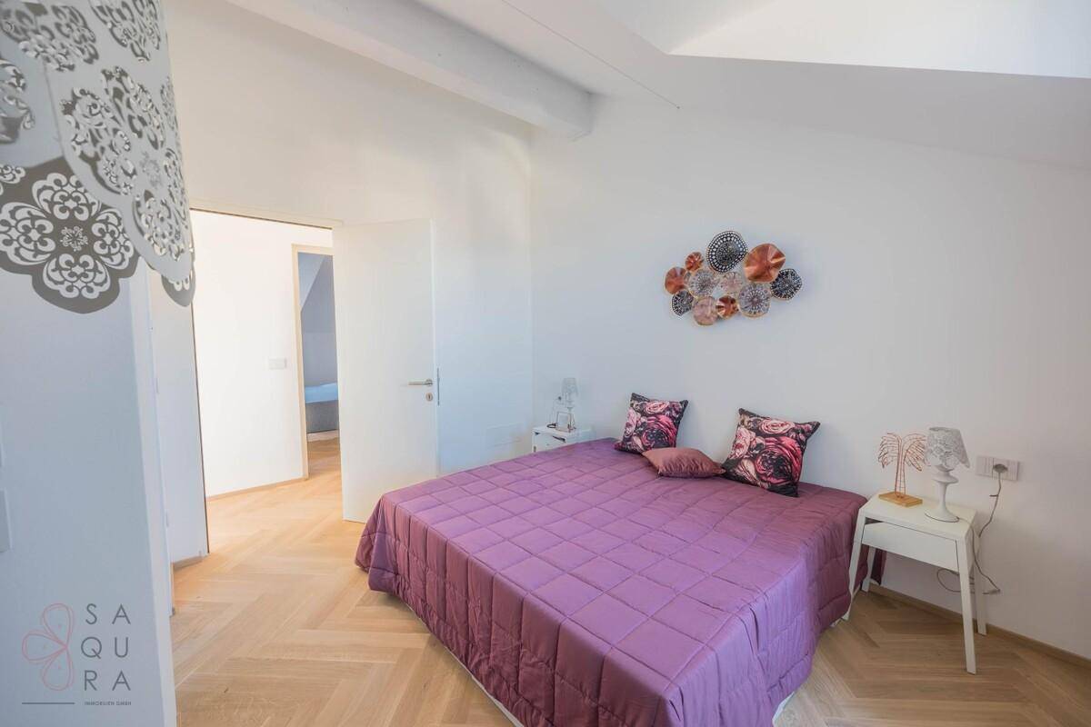 Helles Schlafzimmer mit Doppelbett, Holzboden und moderner Wanddekoration.
