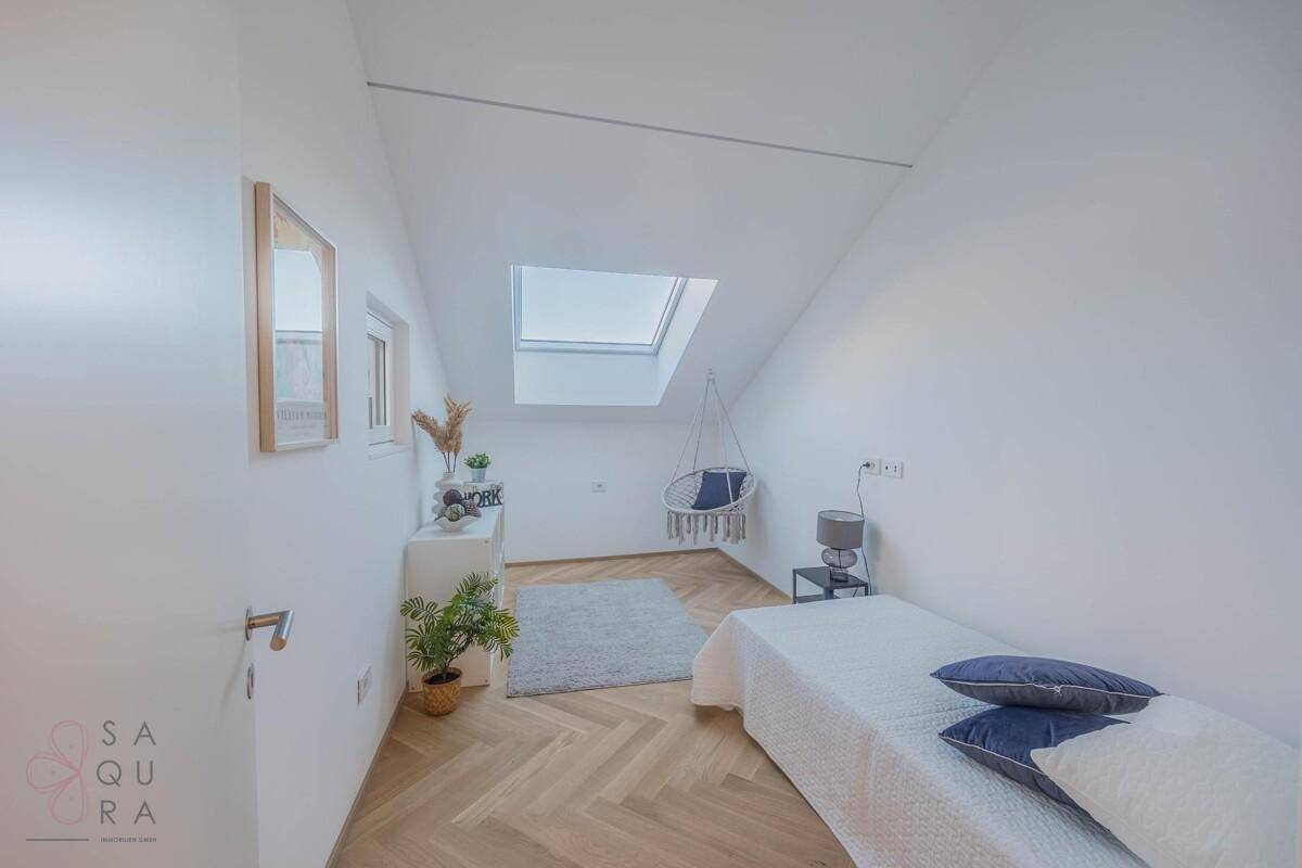 Gemütliches Schlafzimmer im Dachgeschoss mit Einzelbett, Dachfenster und Holzboden.