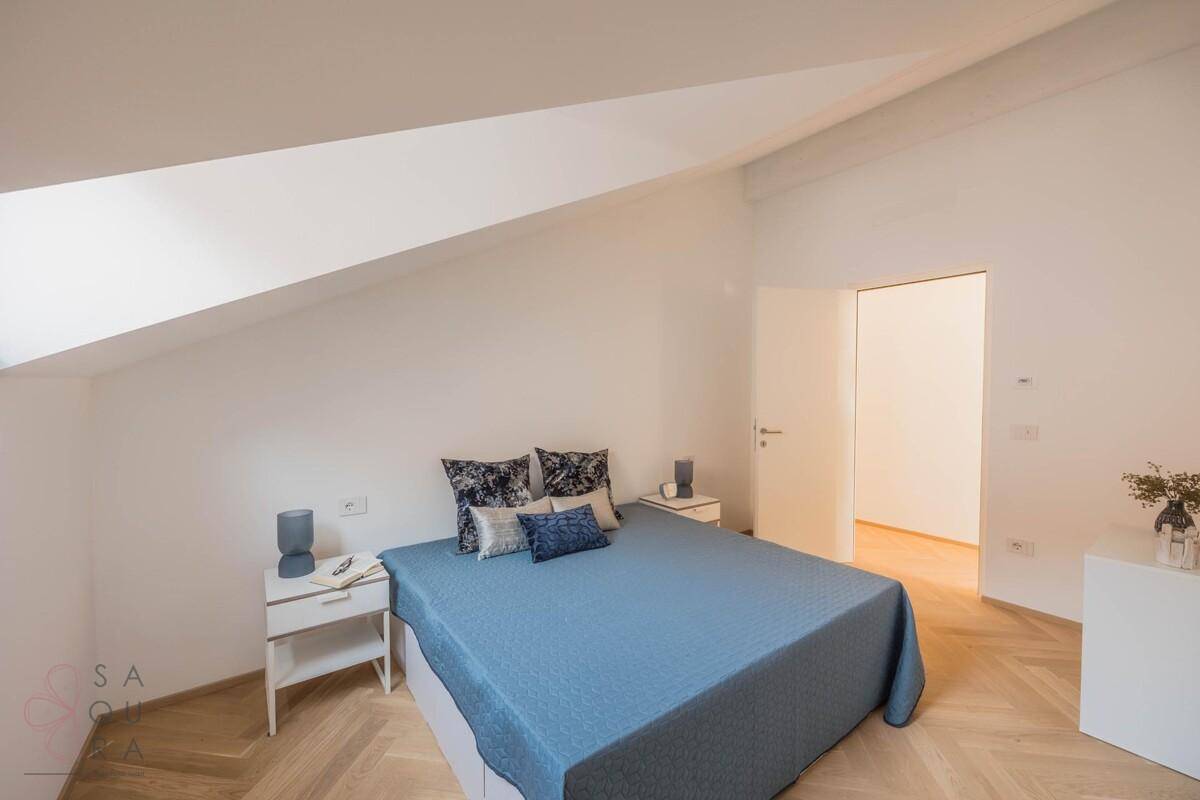 Geräumiges Schlafzimmer mit Doppelbett, Holzboden und schrägen Wänden im Dachgeschoss.