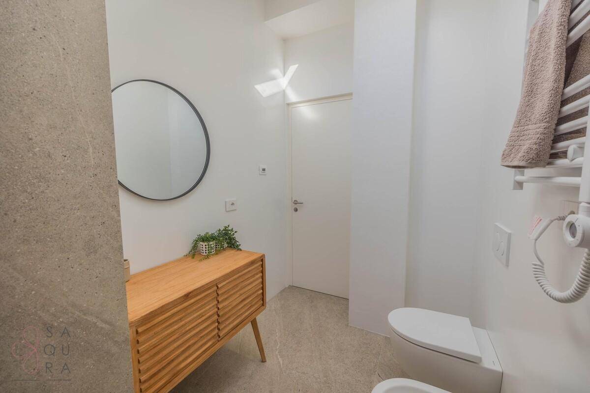 Stilvolles Badezimmer mit Holzwaschtisch, rundem Spiegel und modernen Armaturen unter einem Dachfenster.