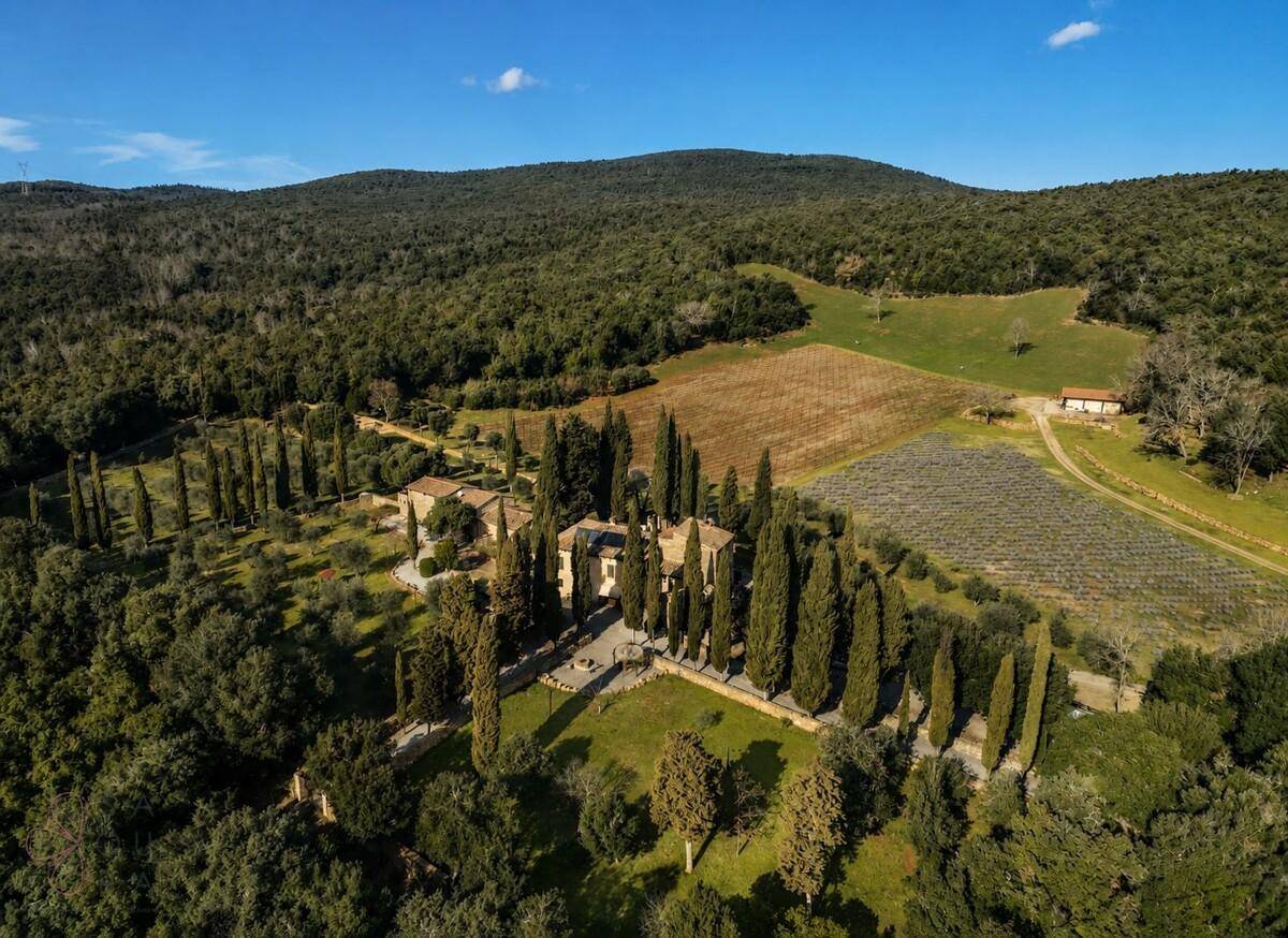 Weitläufiges Anwesen in hügeliger Landschaft mit Zypressenallee und umgebenden Wäldern.