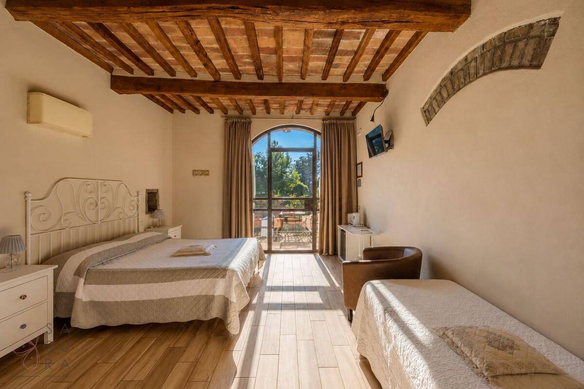 Helles Schlafzimmer mit Holzbalkendecke, Klimaanlage und Zugang zu einem Balkon.