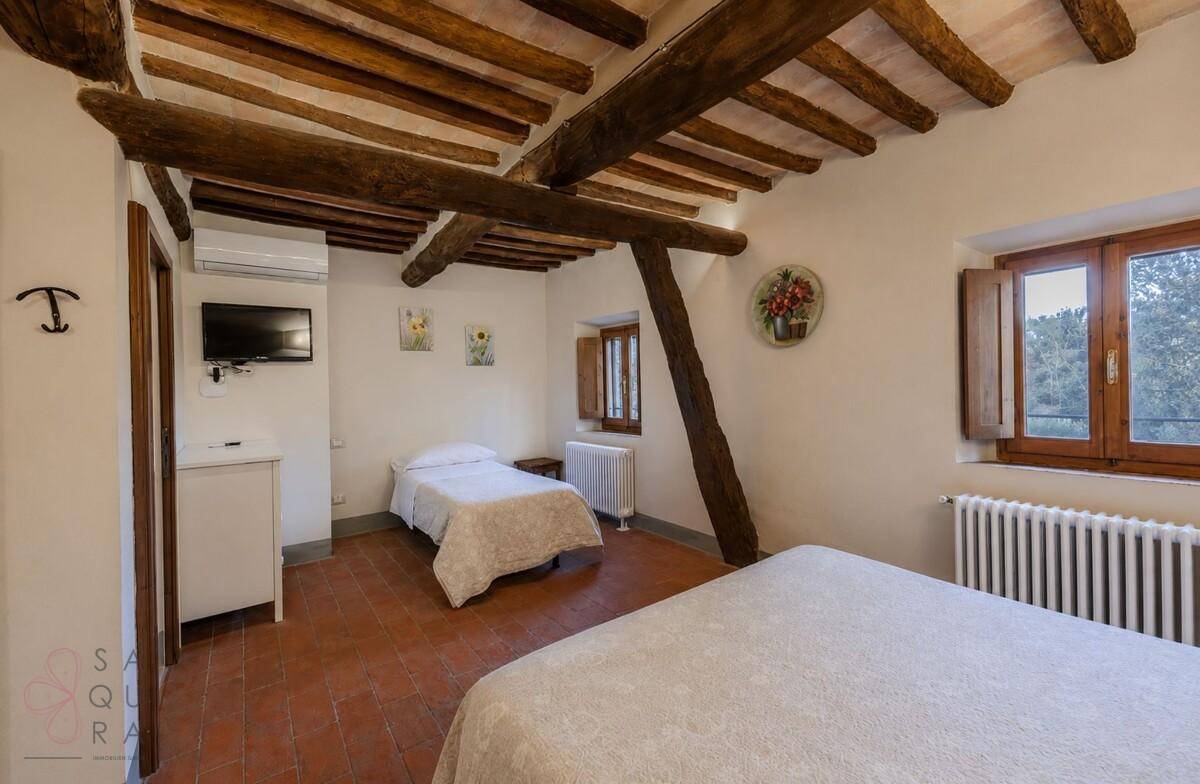 Rustikales Schlafzimmer mit Terrakottaboden, Holzbalkendecke und traditionellen Heizkörpern.